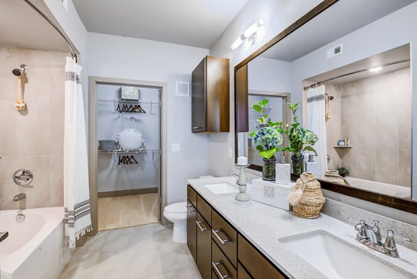 Spacious bathroom with double sinks, large mirror, and walk-in closet in Platform Apartments