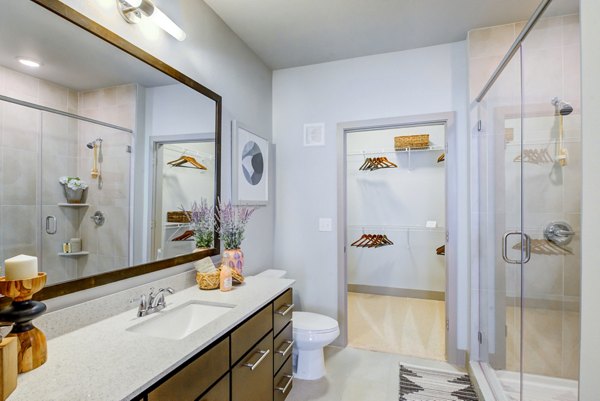 Spacious bathroom with glass shower and large mirror adjacent to a walk-in closet at Platform Apartments