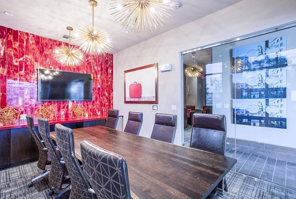 Conference room with red accent wall and starburst chandeliers at Platform Apartments