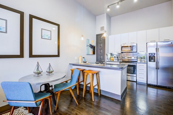 Bright kitchen and dining area with blue chairs and bar stools at Platform Apartments