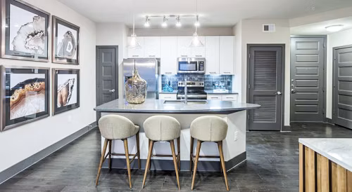 Modern kitchen with island, barstools, and stainless steel appliances in Platform Apartments, luxury living by Greystar