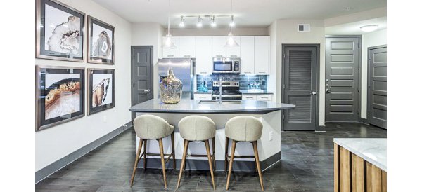 Modern kitchen with island, barstools, and stainless steel appliances in Platform Apartments, luxury living by Greystar
