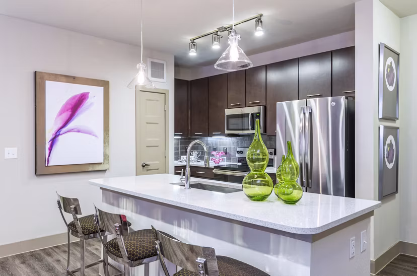 Sleek kitchen with island, bar stools, and stainless steel appliances in Platform Apartments in a vibrant city setting