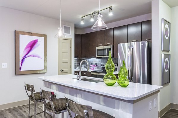 Sleek kitchen with island, bar stools, and stainless steel appliances in Platform Apartments in a vibrant city setting