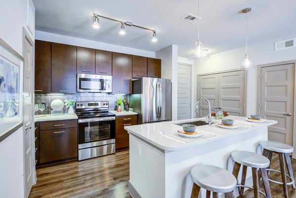Platform Apartments: Sleek kitchen with stainless steel appliances, island, and bar stools for luxury living