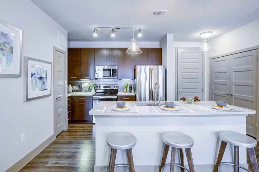 Spacious kitchen with island, bar stools, and stainless steel appliances at Platform Apartments