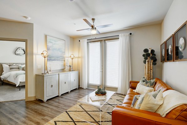 Bright living room with leather sofa, ceiling fan, and artwork at Platform Apartments, luxury apartments by Greystar