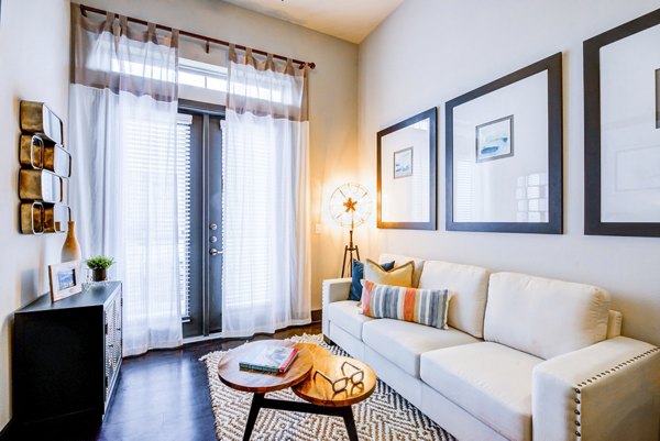 Bright living room with white sofa, framed art, and glass doors at Platform Apartments in Greystar's luxury collection