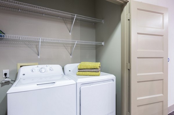 Modern laundry room with washer, dryer, and shelving in Platform Apartments, enhancing convenience and style for luxury living
