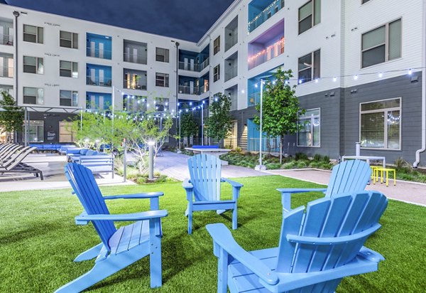 Platform Apartments: Outdoor seating area with blue chairs and string lights in luxury community