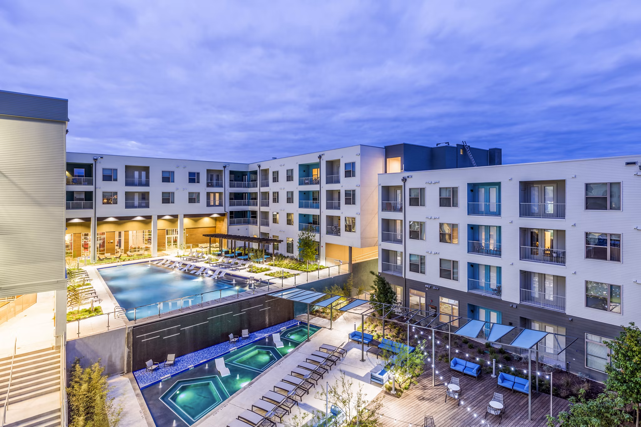 Apartment complex with pool, hot tubs, and outdoor seating area at Platform Apartments