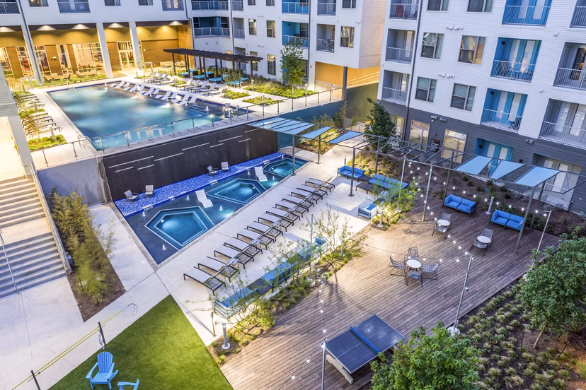 Apartment complex with pool, hot tubs, lounge chairs, and seating area at Platform Apartments