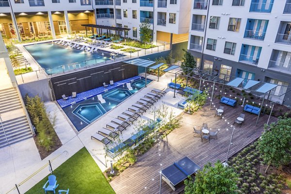 Apartment complex with pool, hot tubs, lounge chairs, and seating area at Platform Apartments