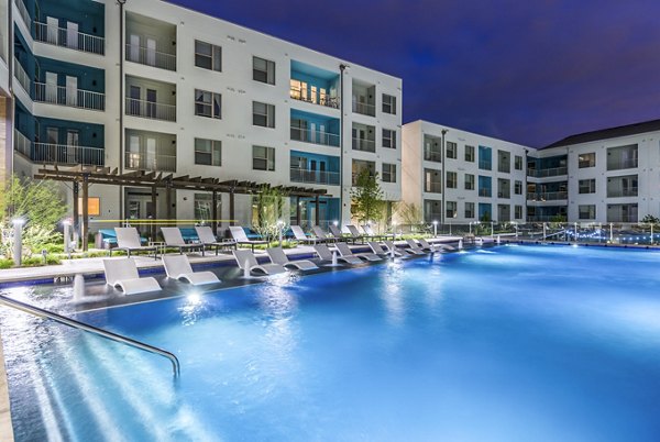 Platform Apartments: Luxury apartment complex with illuminated pool and lounge chairs at night in vibrant urban setting