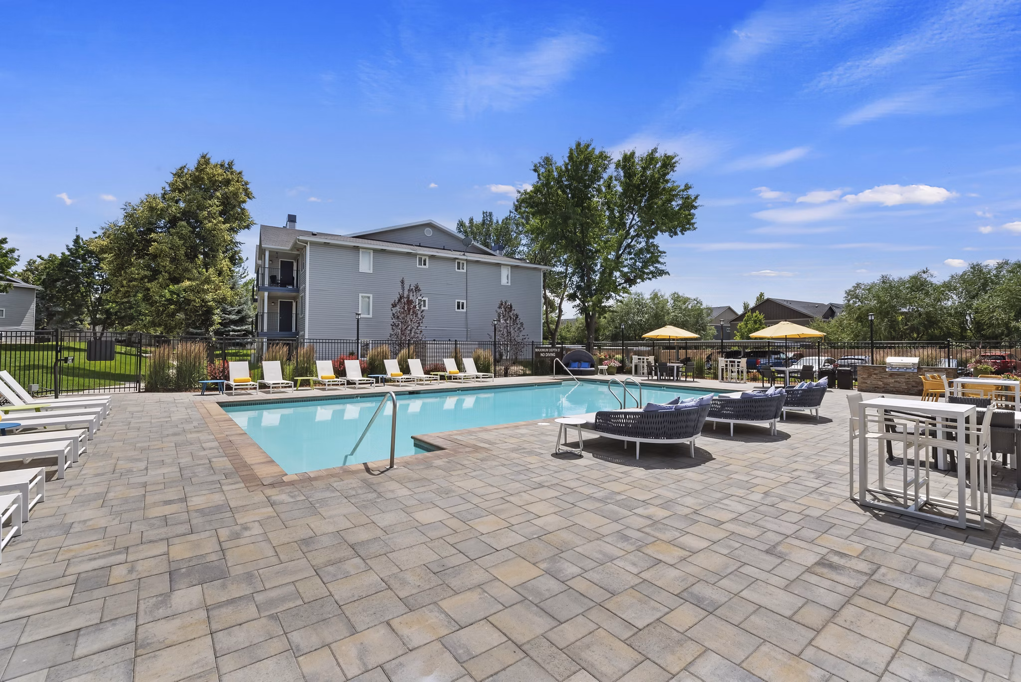 Luxurious poolside area at Rosewood Apartments with loungers and lush landscaping for a relaxing experience