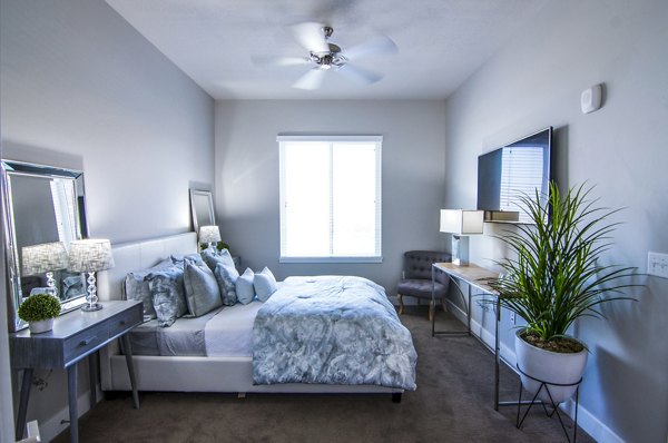 Bedroom with modern decor and large windows at 4th West Apartments, showcasing luxury living spaces in a prime location