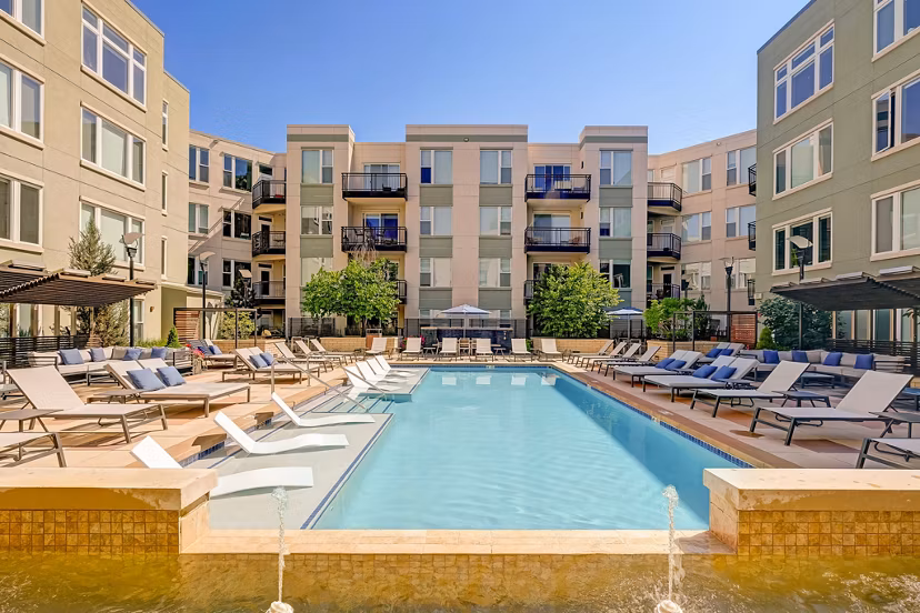Resort-style pool with stylish lounge chairs at Alara Union Station Apartments
