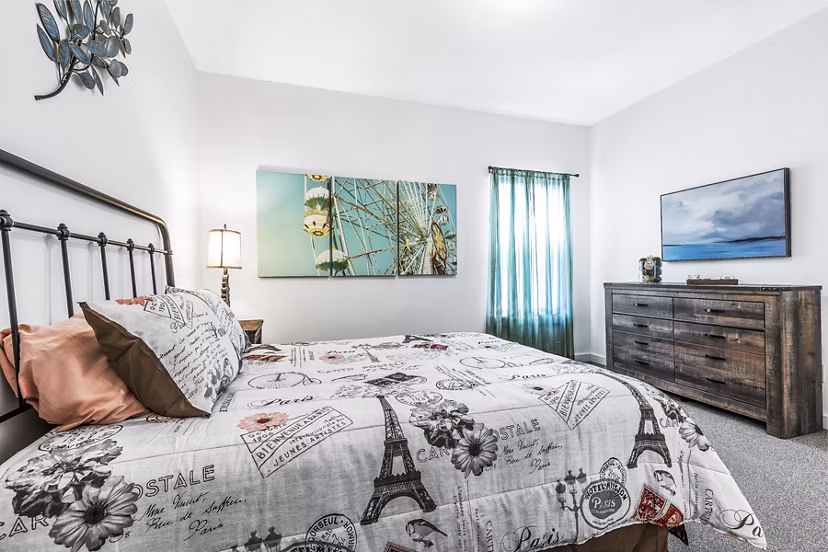 Cozy bedroom featuring modern decor and ample natural light at The Court at Dorel Apartments, a Greystar luxury community