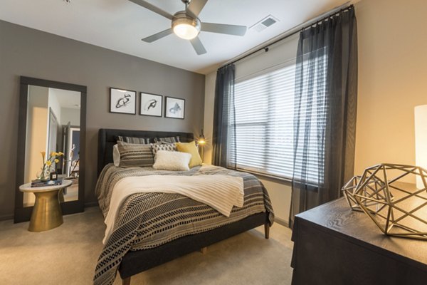 Cozy bedroom with modern decor at Anderson Flats Apartments, featuring large windows and stylish furnishings