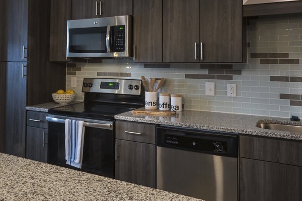 Modern kitchen with stainless steel appliances and granite countertops at Anderson Flats Apartments