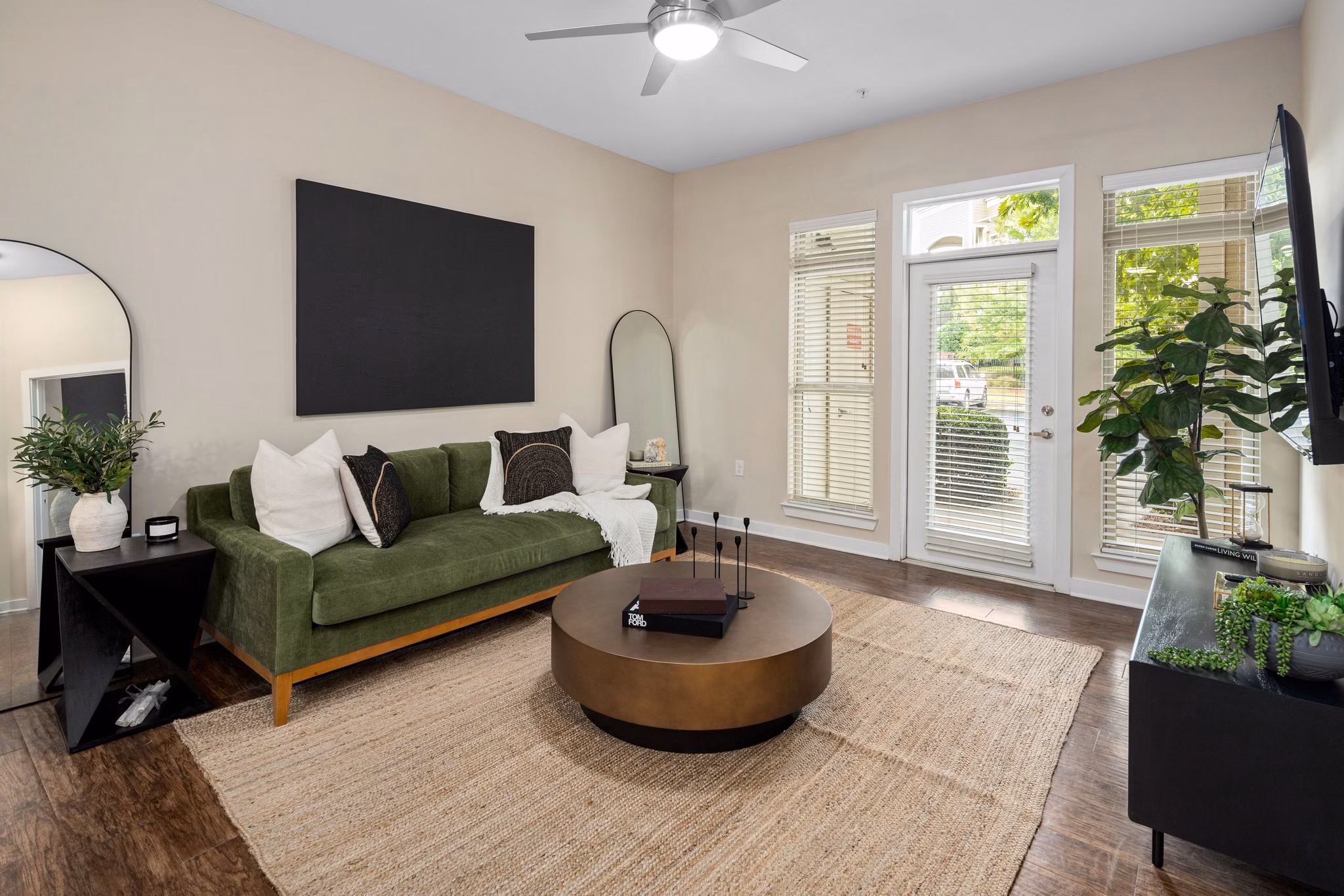 Living room with modern TV, cozy sofa, stylish kitchen, and ceiling fan in 400 Belmont Apartments, a luxury residence by Greystar