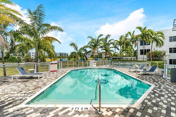 Pool with lounge chairs and palm trees at South of Atlantic (SofA) Apartments offering luxury living