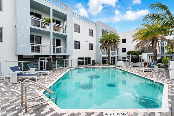 Sparkling pool at South of Atlantic Apartments with lounge chairs and lush landscaping, offering luxury living experiences