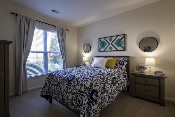 Cozy bedroom with modern decor at Windsor at Tryon Village Apartments, offering luxury living in a welcoming environment