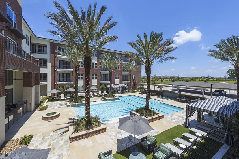 Modern outdoor pool at Overture Sugar Land luxury apartments in Texas, featuring lounge seating and a tranquil garden setting