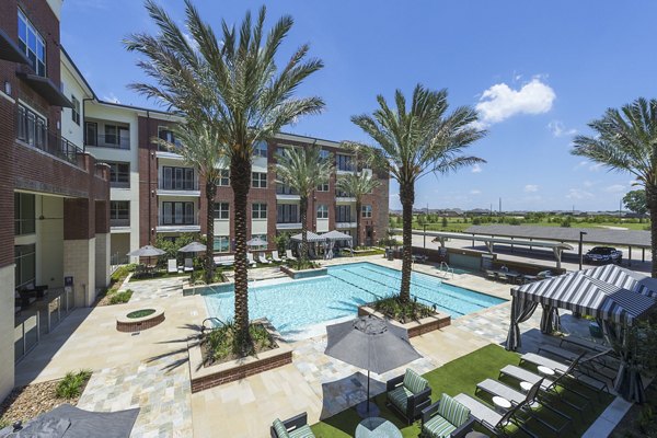Modern outdoor pool at Overture Sugar Land luxury apartments in Texas, featuring lounge seating and a tranquil garden setting