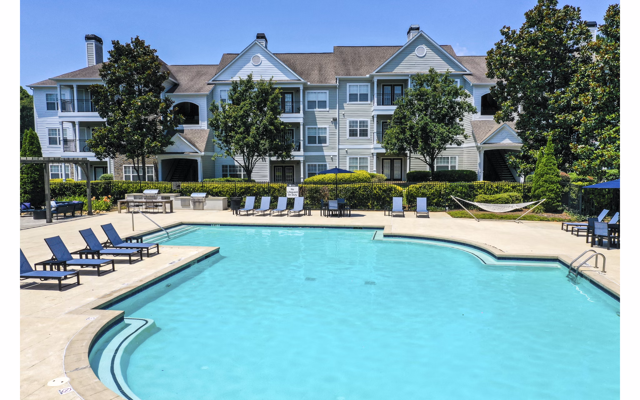 Resort-style pool at Avana North Point Apartments featuring palm trees and lounge chairs