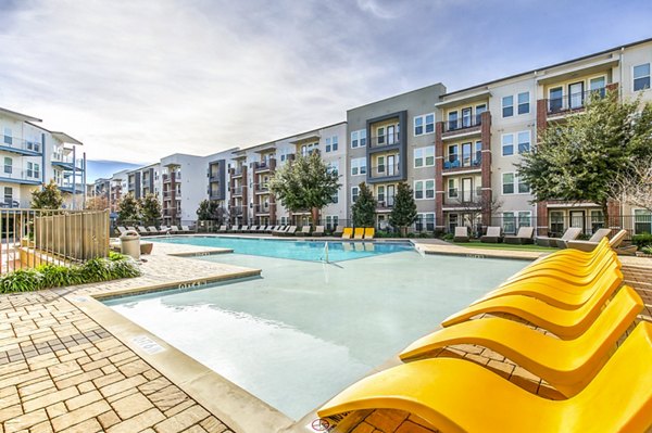 Resort-style pool at Landmark on Lovers Apartments featuring sun loungers and lush landscaping
