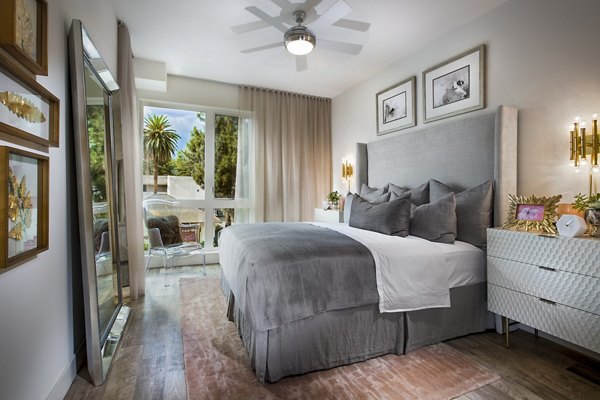 The Hudson Apartments: Cozy bedroom with modern furnishings and ample natural light in luxury apartments