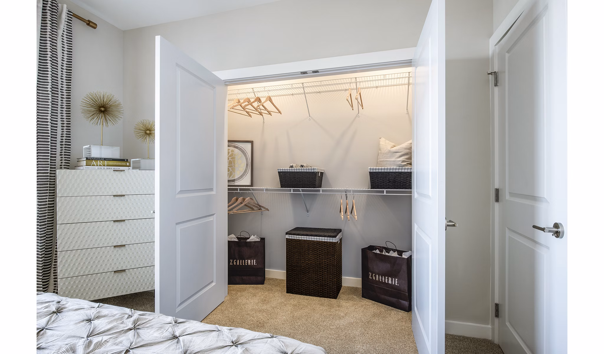 Cozy bedroom with open closet featuring hangers and baskets in luxury apartment
