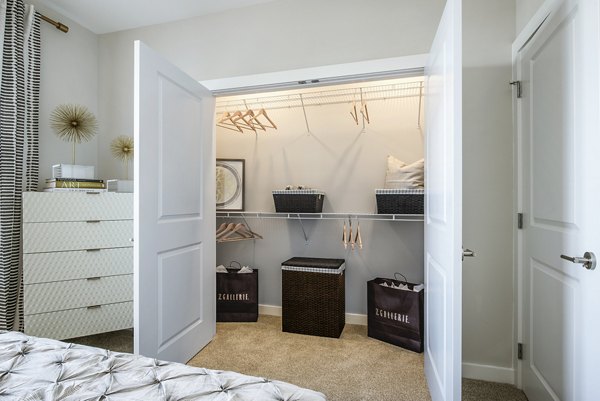 Cozy bedroom with open closet featuring hangers and baskets in luxury apartment