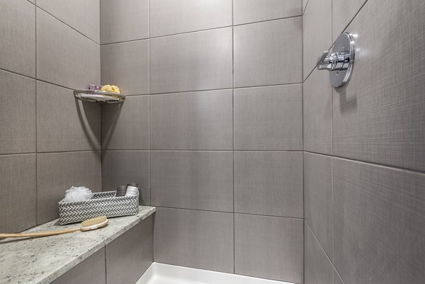 Tiled shower area with built-in shelf for toiletries at luxury apartments