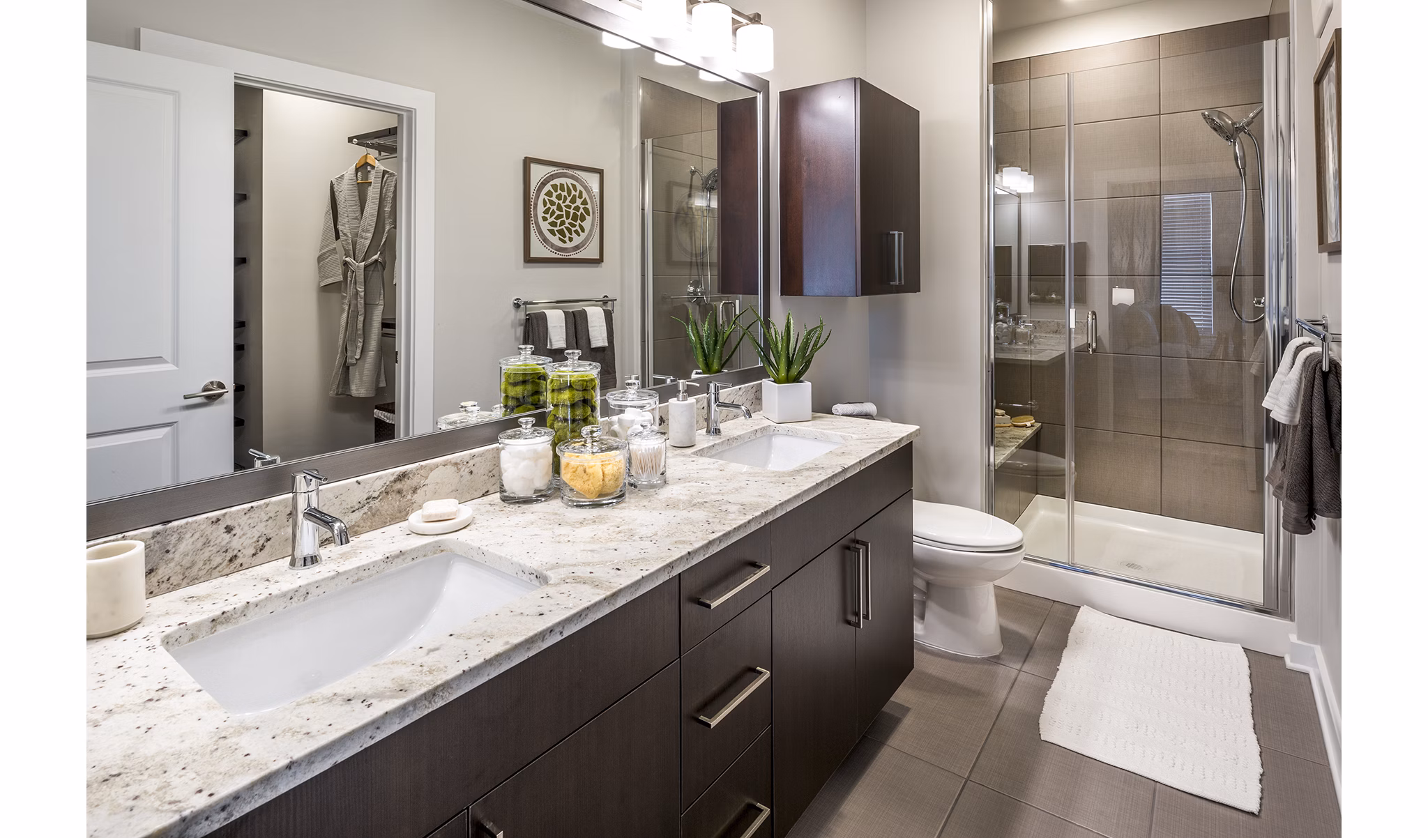 Modern bathroom featuring a double sink vanity and glass-enclosed shower with decorative accents