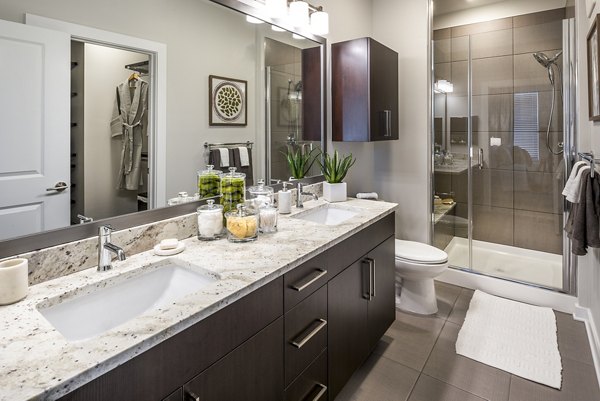Modern bathroom featuring a double sink vanity and glass-enclosed shower with decorative accents