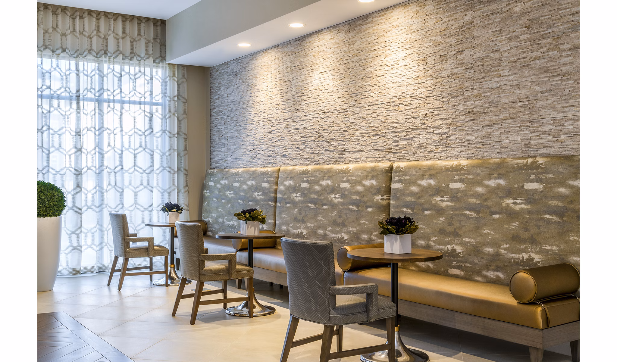 Stylish seating area with modern tables, cushioned bench, and decorative plants in luxury apartments