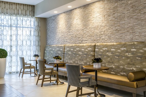 Stylish seating area with modern tables, cushioned bench, and decorative plants in luxury apartments