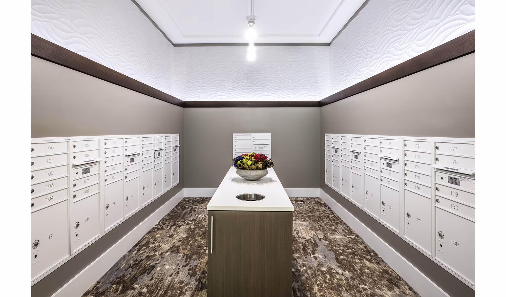 Mailroom with multiple mailboxes and a central table in luxury apartment community