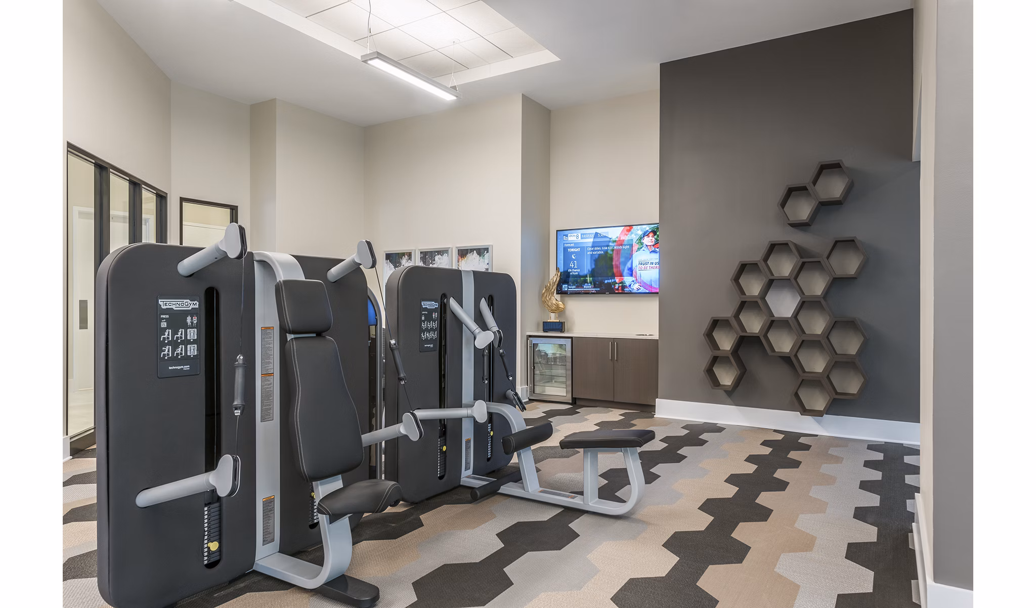 Modern gym with exercise equipment and a TV in luxury apartments