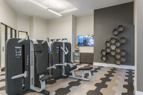 Modern gym with exercise equipment and a TV in luxury apartments