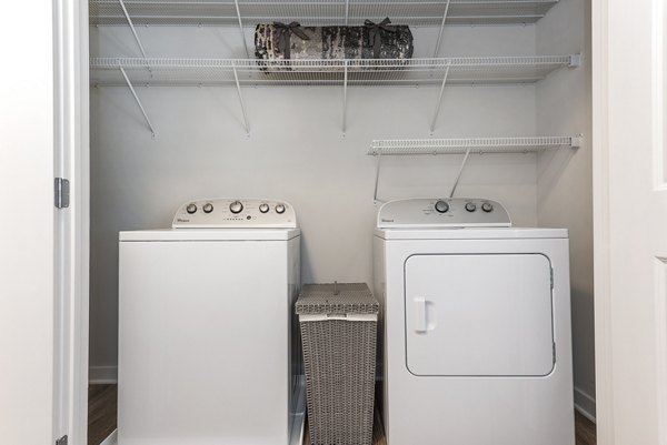 Laundry area featuring a washing machine and dryer with shelves in luxury apartments