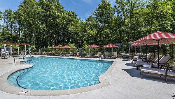 Resort-style pool surrounded by lounge chairs at Overture Fair Ridge Apartments