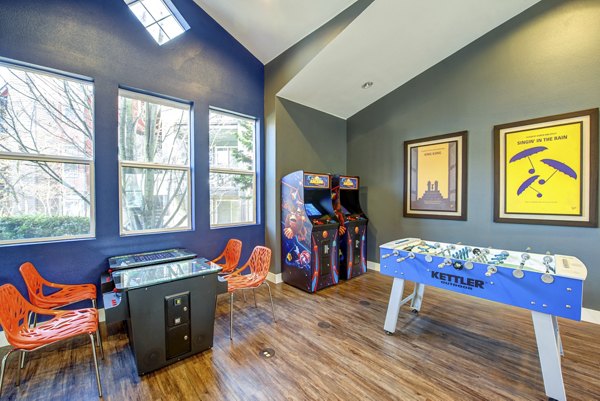 Game room with shuffleboard table and plush seating at Avana One Six Four Apartments