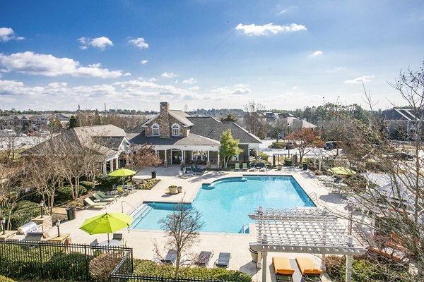 Poolside lounge area at Andover at Johns Creek Apartments with sun chairs and greenery Enjoy leisure and relaxation in this inviting outdoor space