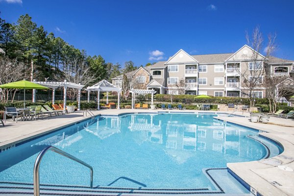 Luxurious swimming pool at Andover at Johns Creek Apartments, surrounded by lush landscaping and modern seating areas