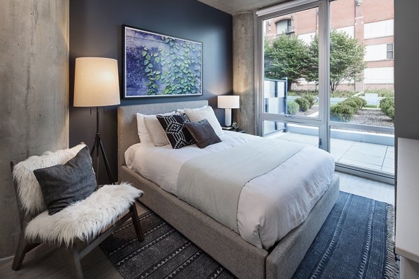 Luxurious bedroom with modern furnishings at 1401 S State Apartments, featuring plush bedding and city views