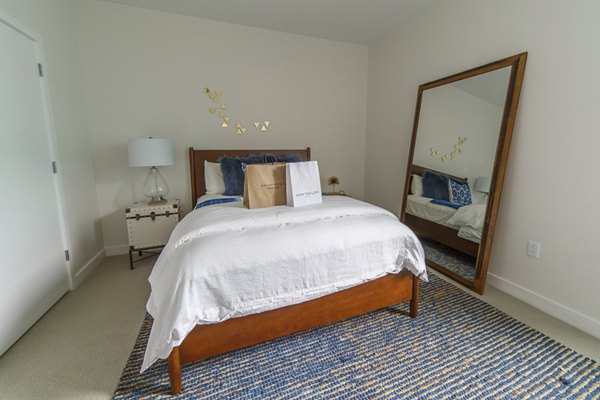 Modern bedroom with plush bedding at Montaje Apartments, featuring natural light and sleek decor